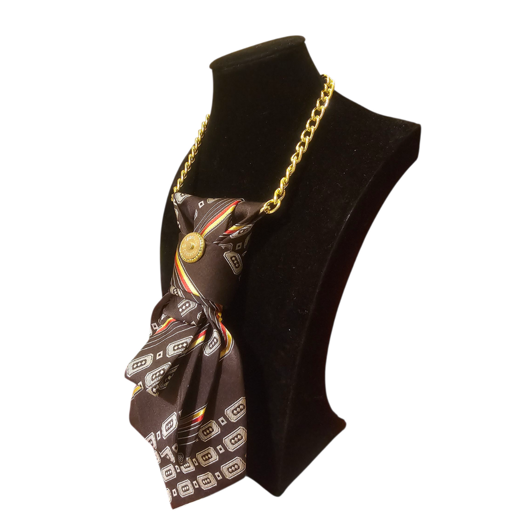 Collana-cravatta marrone con spilla dorata che funge da aggancio magnetico per Clap Calamita. Pezzo unico di design sostenibile made in Italy.