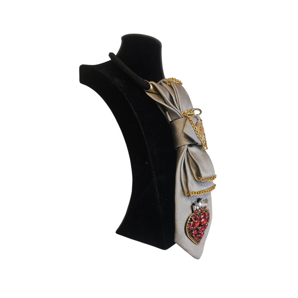 Cravatta gioiello donna componibile grigio chiaro con cuore ex voto rosso, strass e catene metalliche su manichino posizione laterale verso sinistra