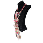 Cravatta Gioiello Rose Gold in tessuto seta rosa e rosso con charm scultoreo a forma di lisca di pesce in oro rosa su manichino, posizione laterale