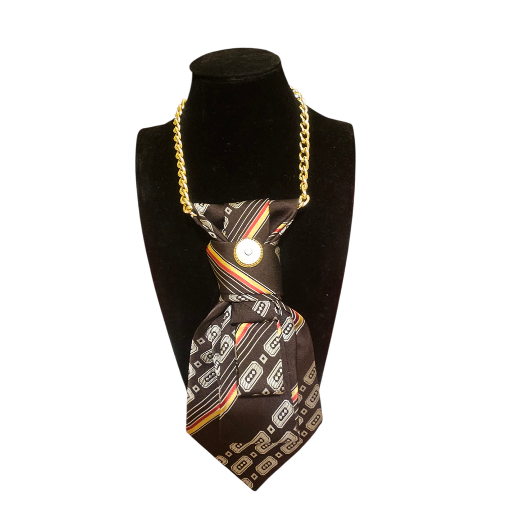 Collana-cravatta artigianale in raso marrone con motivi geometrici, catena dorata regolabile e spilla vintage a clip dorata che funge da aggancio per Clap Calamita. Pezzo unico realizzato a mano in Italia.