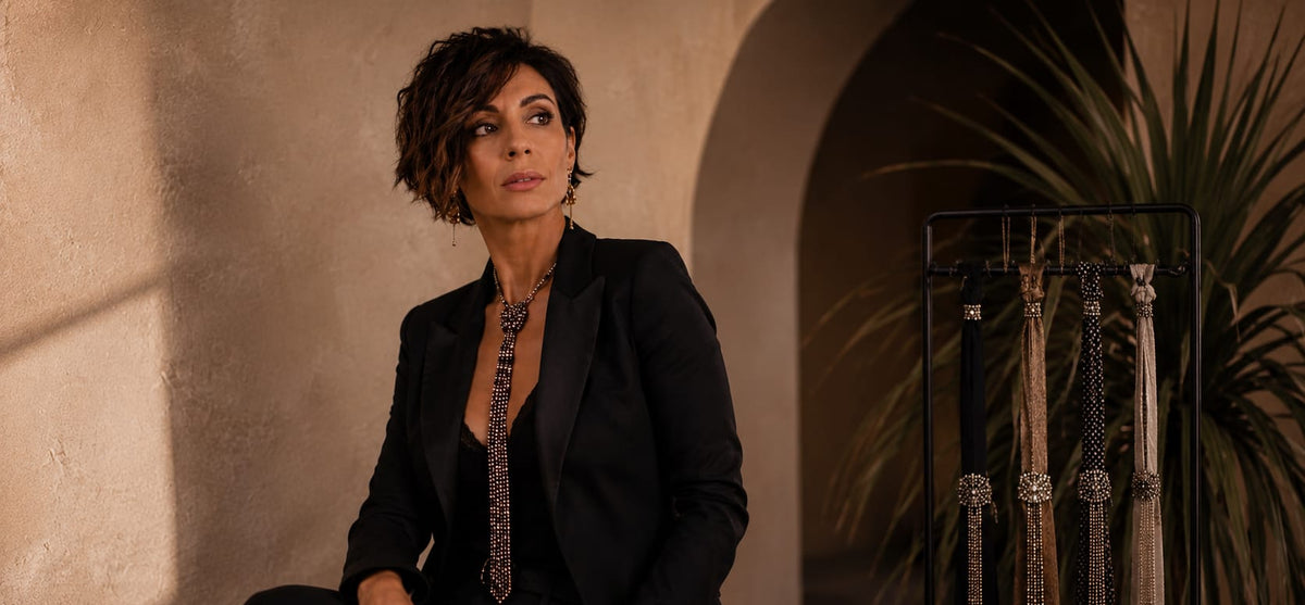 claudia de rosa è seduta su un tavolino e alle spalle ha esposizione di cravatte Gioiello componibili